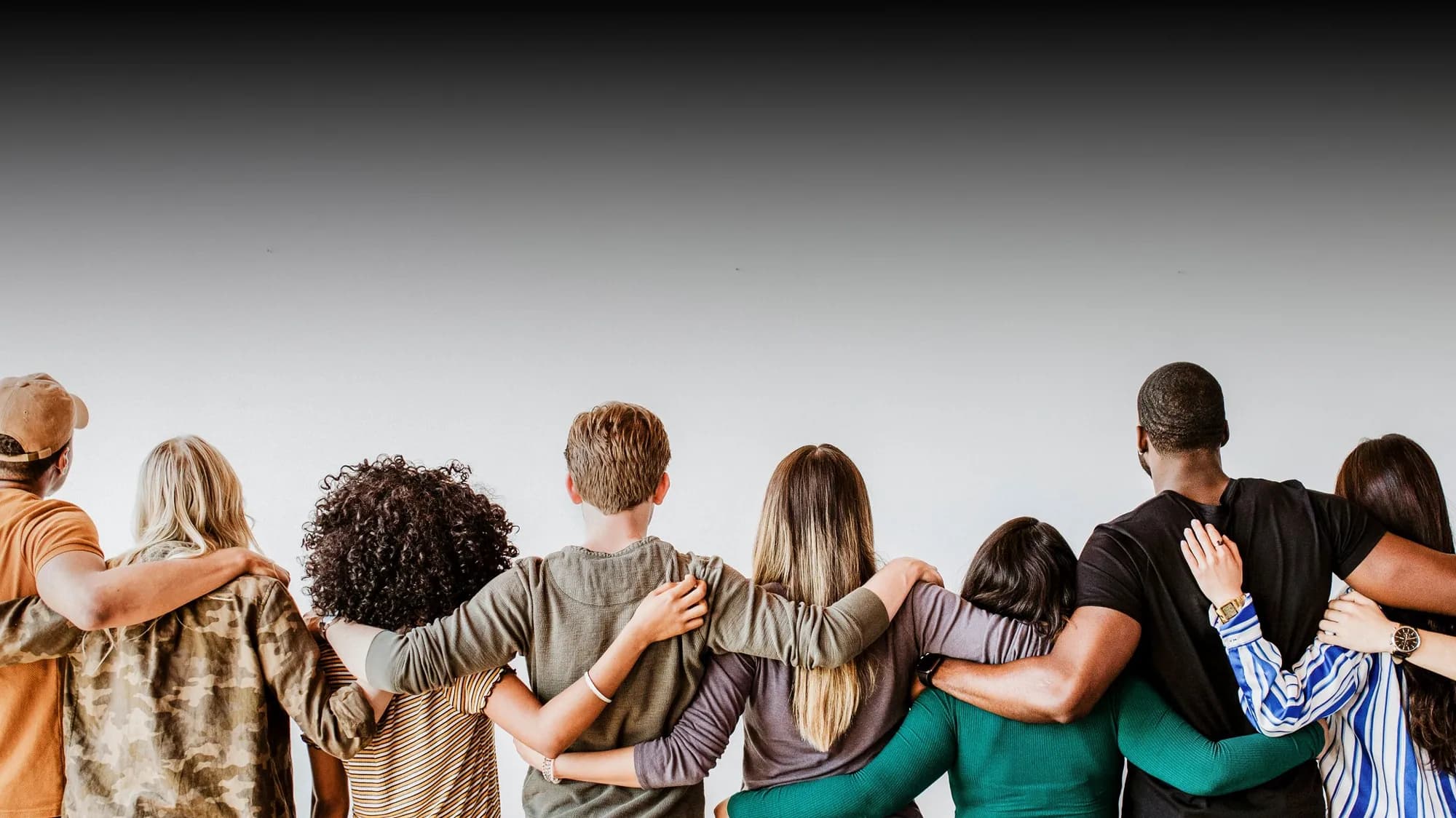 A diverse group standing together with their arms around one another