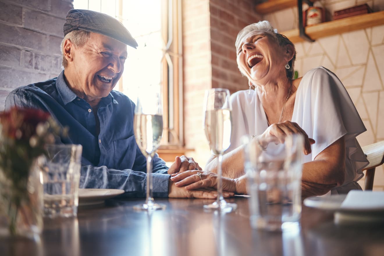 Older couple laughing together over a restaurant meal